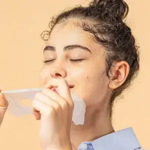 Young lady removing snail mucin mask from face pleased satisfied expression skincare results peel-off mask application brightening treatment